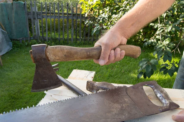 Muž drží sekeru, pracuje se stavebními nástroji ve své zahradě — Stock fotografie
