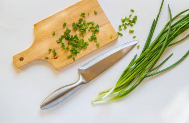 Tahtada doğranmış yeşil soğan, beyaz izole edilmiş arka planda bıçak, sağlıklı organik gıda kavramı.