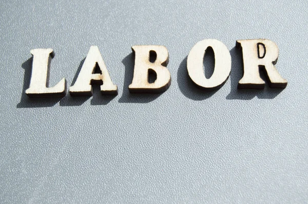 The word work written with wooden letters on a gray background, the sunlight, ready for the layout design, the concept of the holiday labor Day