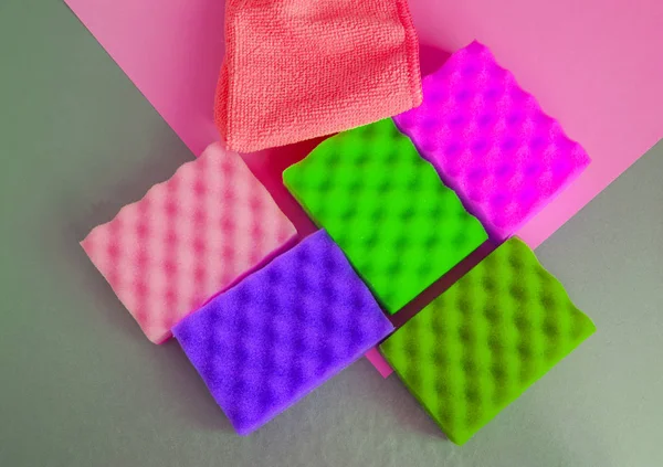 A set of multi-colored sponges and rags for cleaning and cleanliness on a gray background, the concept of outsourcing cleaning company, top View
