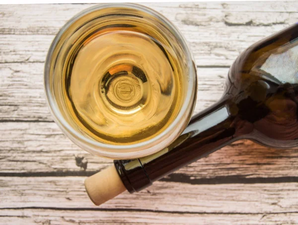 Vista dall'alto di un bicchiere di vino bianco secco e una bottiglia adagiata su un vecchio sfondo di legno — Foto Stock