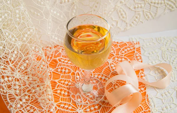 Flache Stapelung von Weißwein im Glas, beige Spitze und dekorative Schleife, orangefarbener Hintergrund, Draufsicht. romantische Frühlings- oder Sommerkomposition — Stockfoto