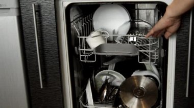 Kadın elleri bulaşık makinesini açar ve temiz parlayan bulaşıkları çıkarır, gösterir. Ev işlerine yardım etmek için modern teknolojiyi kullanıyorlar.
