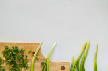 Taze yeşil soğan tüyü ve izole derilerde kullanılmak üzere fotoğrafın alt kenarında bulunan bir kesme Tahtası üzerinde yatan parçalar halinde dilimlenmiş
