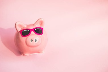 Pembe arka plan üzerinde güneş gözlüğü Komik piggy Bankası, güneş ışığı, kopya alanı, yaz tatili için para tasarrufu kavramı