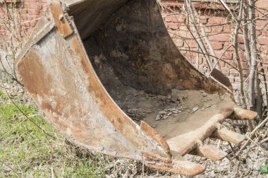 Tuğla duvar arka plan üzerinde eski, paslı ve kirli ekskavatör kova closeup