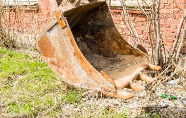 Tuğla duvar arka plan üzerinde eski, paslı ve kirli ekskavatör kova closeup