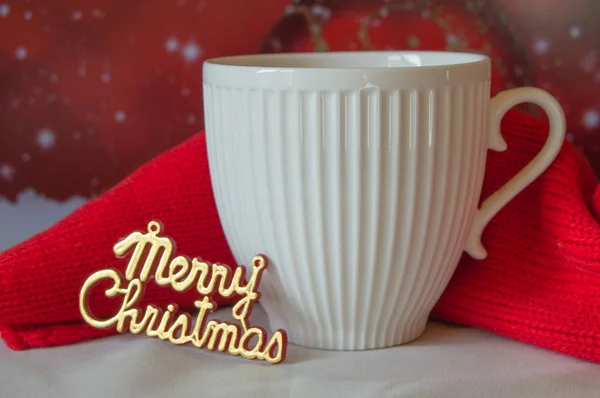 Valkoinen kuppi kahvia ja neulottu punainen huivi, sanat Hyvää joulua — kuvapankkivalokuva