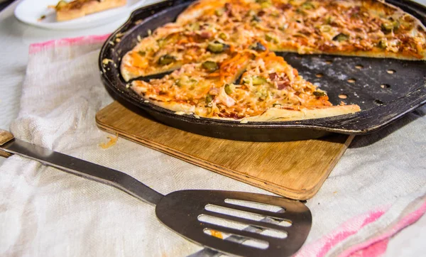 Свежая выпечка аппетитная домашняя пицца на металлической сковороде с сыром и ветчиной, крупным планом избирательного фокуса — стоковое фото