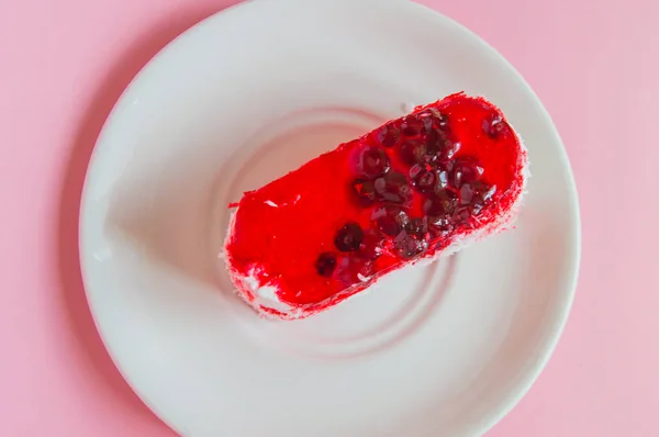 Gyönyörű puding torta vörösáfonya zselével, bogyós máz és kókusz egy fehér lemezen, felülnézetben közeli, rózsaszín háttér — Stock Fotó