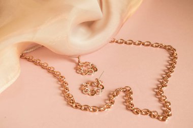 Lüks altın takı zinciri ve ipek ile pembe arka plan üzerinde küpe, kopya alanı, seçici odak