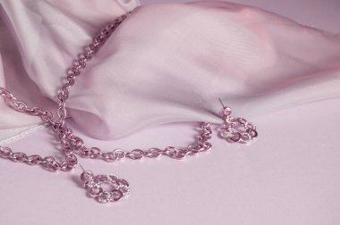 Lüks altın takı zinciri ve ipek ile pembe arka plan üzerinde küpe, kopya alanı, seçici odak