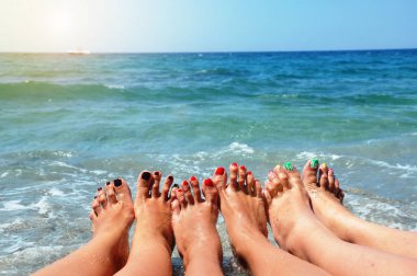 Üç genç kızların ince bacakları kapatın. Arka planda, bir plaj tatil kavramı mavi deniz