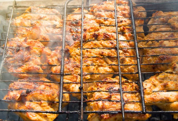 Apetitivos trozos fritos de carne de barbacoa en la parrilla de hierro al aire libre, luz solar, rayos, fondo de alimentos —  Fotos de Stock