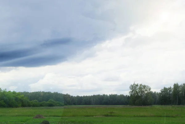 Драматическая сцена бури с серыми облаками в поле, солнечный свет прорывается сквозь облака — стоковое фото