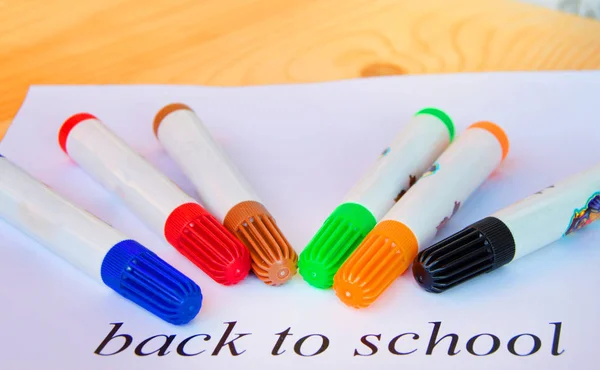 De volta à escola. Uma folha de papel com texto e marcadores coloridos em um fundo de madeira, foco seletivo — Fotografia de Stock