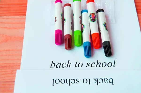 Vissza az iskolába. Papírlap szöveggel és színes markerek egy fából készült háttérrel, felülnézet — Stock Fotó