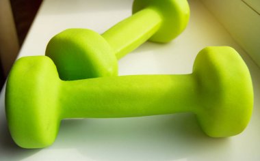 Fitness kavramı, spor için sağlıklı yaşam tarzı-iki yeşil halter, güneş ışığı