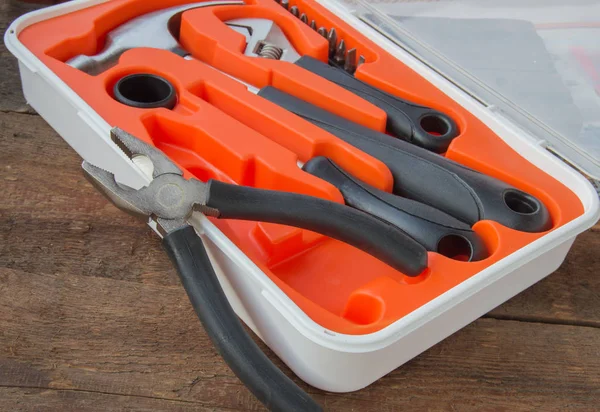 Tool kit pliers, hammer, screwdriver in orange plastic case on old wooden Board with copyspace — Stock Photo, Image