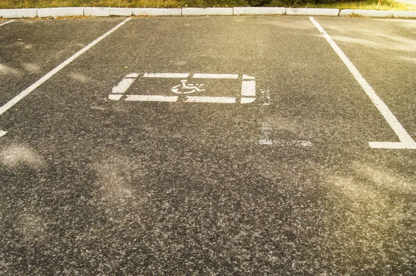 Parking sign for disabled people painted on the asphalt in an empty Parking lot, sunlight