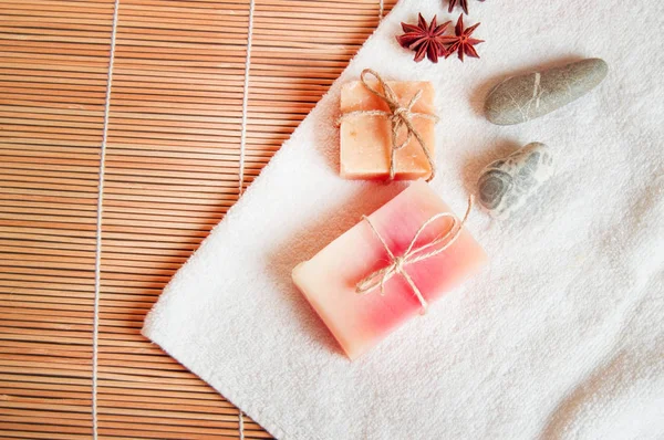 Ajuste de spa con toalla blanca, jabón hecho a mano, piedras, sobre fondo de bambú natural, espacio para copias planas —  Fotos de Stock