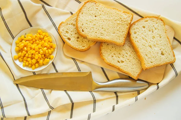 Свежеиспеченный традиционный хлеб пшеницы, кукурузные зерна и нож на льняном кухонном полотенце, плоский лежал — стоковое фото