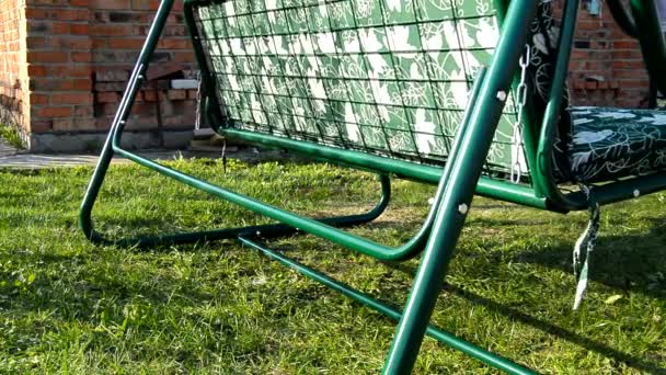Cama de balanço de metal nova moderna com colchão balançando no gramado no jardim de verão — Vídeo de Stock