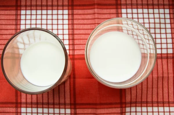 Dois copos de suporte de leite em um pano xadrez vermelho, vista superior — Fotografia de Stock