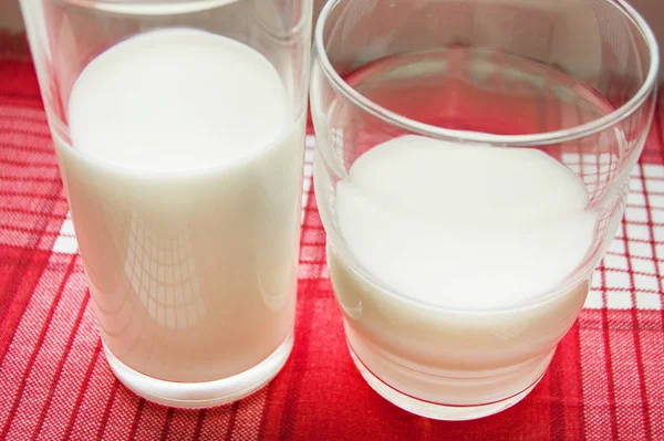 Dos vasos de leche en un paño rojo a cuadros, concepto de comida saludable — Foto de Stock