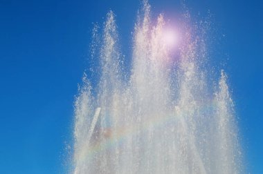 Güneşli bir yaz gününde su jetleri ve mavi gökyüzüne karşı sıçramaları ile Parkta Çeşme