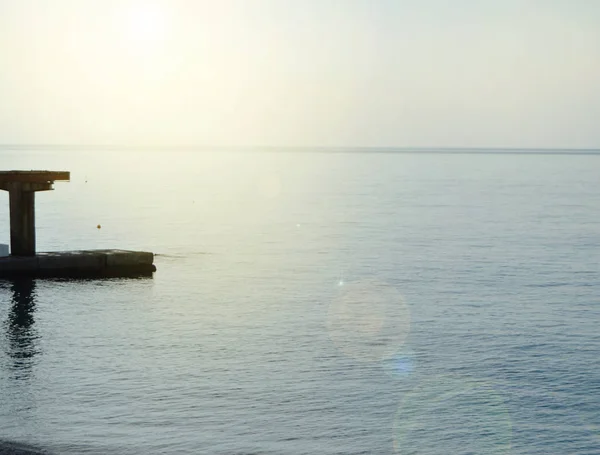 Soluppgång på havet med sol bländning, pir på stranden i tidig morgon, lugn, vila, sommarsemester koncept — Stockfoto