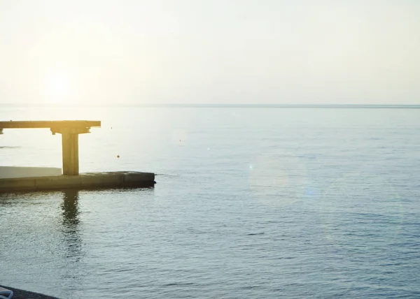 Soluppgång på havet med sol bländning, pir på stranden i tidig morgon, lugn, vila, sommarsemester koncept — Stockfoto