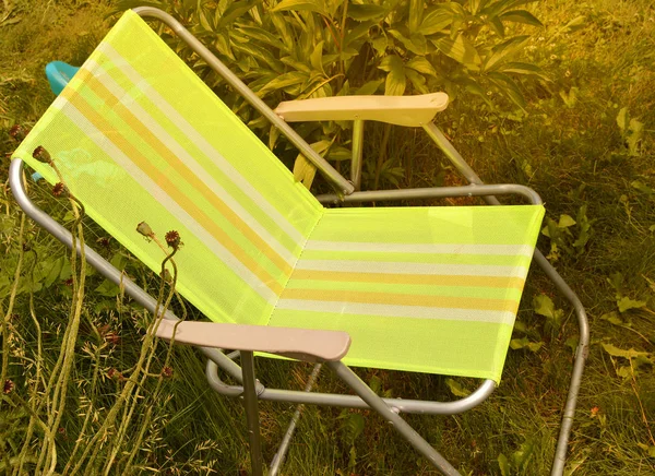 Chaise pliante camping est situé dans le jardin sur l'herbe par une journée d'été ensoleillée — Photo