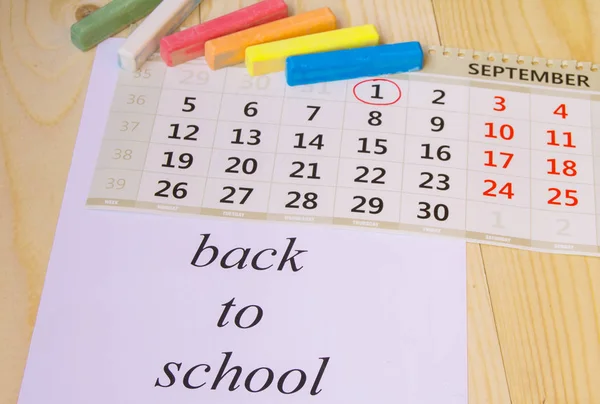 Voltar à escola, calendário, giz colorido em fundo de madeira — Fotografia de Stock