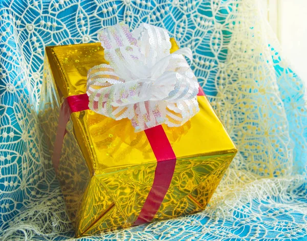 Caja de regalo en paquete de lámina de oro con lazo blanco, hermoso fondo azul de Navidad, concepto de Navidad — Foto de Stock
