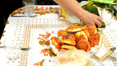 Bir kadın aile için açık havada öğle yemeği hazırlar, yeşil soğan ve sebzeleri güzel bir keten masa örtüsünün üzerine taze hamur işlerinin yanına serer, bahçede bir yaz günü ev yapımı organik yiyecekler.