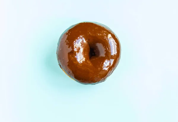 Dlicious Donut mit einer glänzenden Schokoladenspiegelglasur isoliert auf blauem Hintergrund. der Blick von oben — Stockfoto