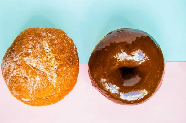 Två munkar med florsocker och choklad grädde på pastell rosa och blå bakgrund, uppifrån, Flatlay, ljus och mörk — Stockfoto