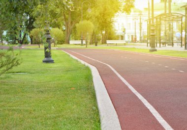 Yeşil çim ente ve ağaçların bir arka plan üzerinde Güneşli bir yaz gününde Parkta Jogging için Modern koşu bandı trekking, metin için bir yer