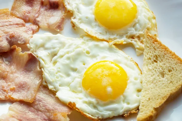 Heerlijk ontbijt - witte plaat van gebakken eieren, bacon en toast — Stockfoto