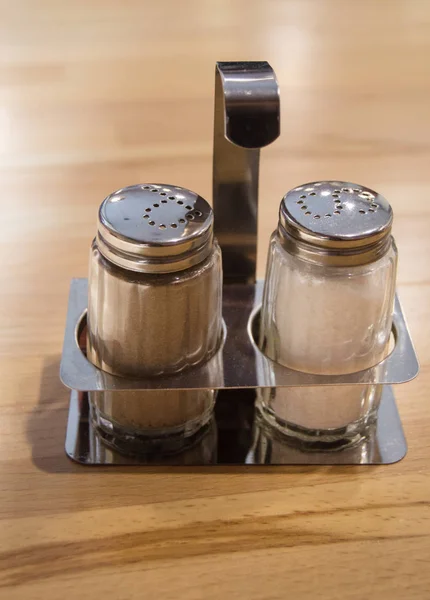 Agitador de sal y pimienta de vidrio y metal establecido en la mesa de madera en la cafetería, de cerca, marco vertical — Foto de Stock