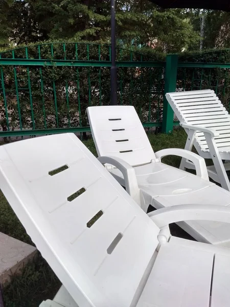 空白色塑料躺椅站在户外泳池附近的草地上 在炎热的夏日 在度假村放松的概念 — 图库照片