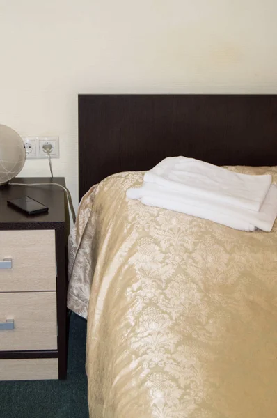 Вертикальний знімок інтер'єру спальні готелю з порожнім односпальним ліжком з дерев'яним узголів'ям, тумбочкою і рушниками на ліжку, копія простору — стокове фото