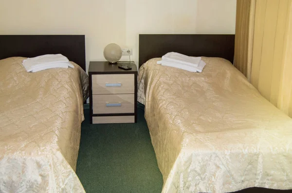 Modern double room with two single beds, bedside table, towels and table lamp, cozy inexpensive room for travelers, good service and hospitality of the hotelier