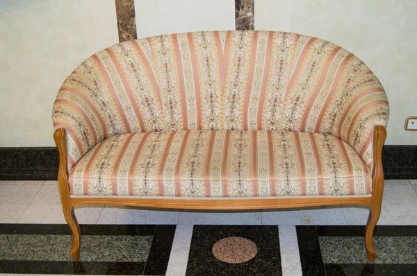 Klasyczna elegancka sofa z tapicerką tekstylna i drewnianymi nogami, wykonana w stylu retro, marmurowa podłoga i ściany w salonie luksusowego hotelu — Zdjęcie stockowe