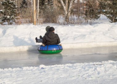 Çocuklar şişme bir tüp üzerinde buz slaytlar ile binmek, kaygan buz üzerinde yüksek hızlı slayt, kış eğlence ve şehir Park açık hava etkinlikleri
