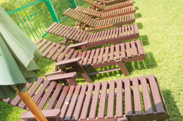 Liegestühle aus Holz stehen in einer Reihe auf dem grünen Rasen unter der Sonne im Erholungsgebiet auf dem Privatgelände eines modernen Luxushotels. Garten zum Sonnenbaden und Entspannen — Stockfoto