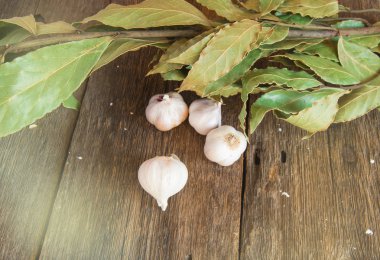 Defne yaprağı dalı ve sarımsak başları ile koyu ahşap rustik arka plan, Akdeniz baharatları için temel