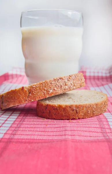 Close-up of Sliced rye bread and a glass of milk on a cloth red napkin, rustic background, healthy food, vertical shot