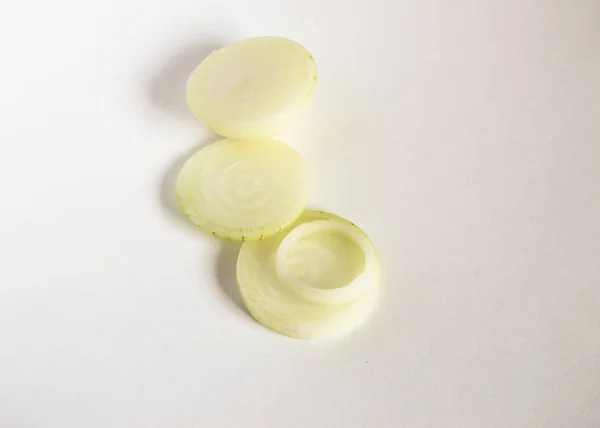 Weiße Zwiebeln in runde Stücke auf weißem Hintergrund geschnitten, das Konzept der Verwendung von gesundem Gemüse in der Küche — Stockfoto